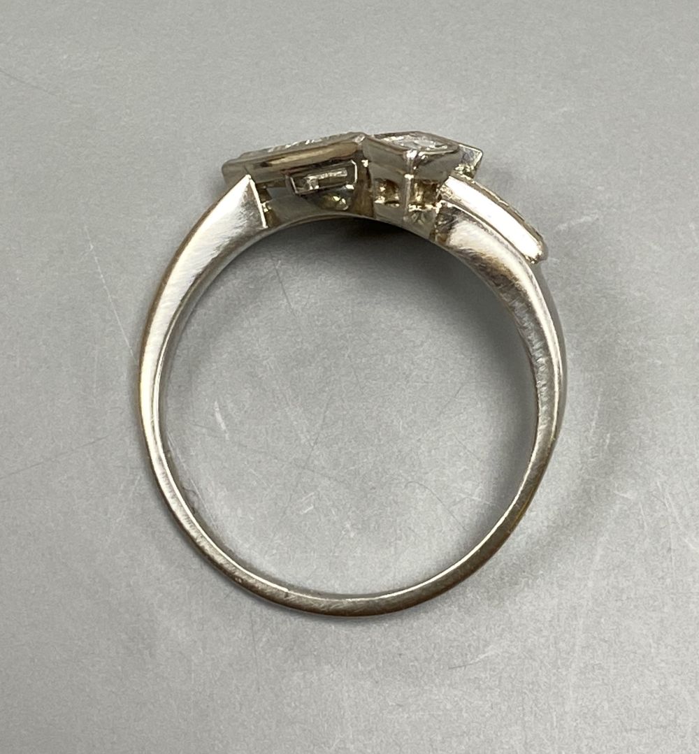 An unusual white metal (stamped Plat), triangular, square and graduated baguette cut diamond cluster set dress ring,